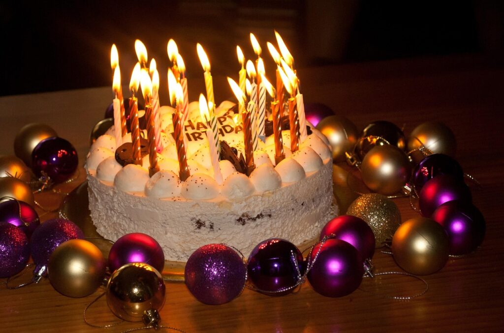 Geburtstag an Weihnachten: Diese Promis feiern am 24., 25. und 26. Dezember Geburtstagstorte mit brennenden Kerzen zwischen Christbaumkugeln
